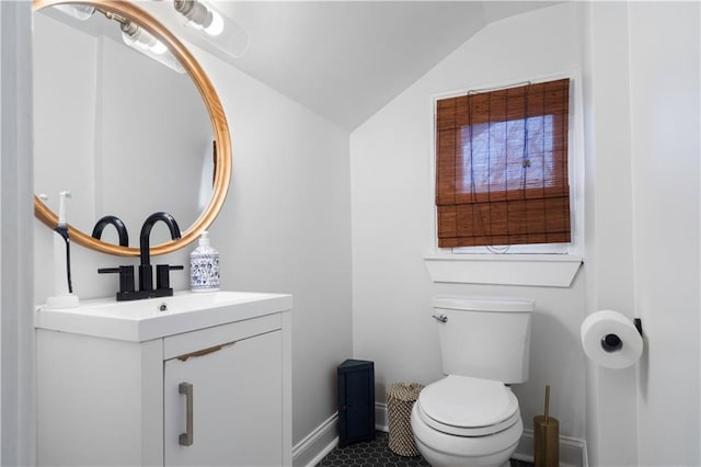 half bathroom featuring vanity, vaulted ceiling, toilet, and baseboards