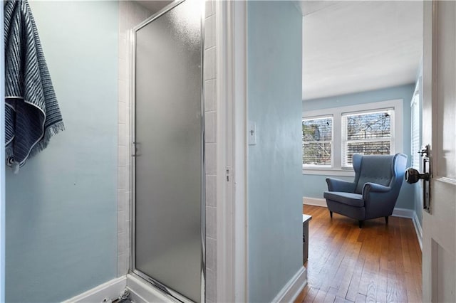 full bathroom with baseboards, wood-type flooring, and a stall shower