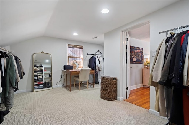 walk in closet featuring visible vents, lofted ceiling, and carpet