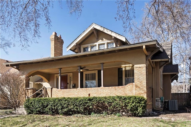 view of front facade with a chimney, brick siding, central AC unit, and a ceiling fan