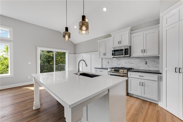 kitchen with a healthy amount of sunlight, vaulted ceiling, stainless steel appliances, and a sink