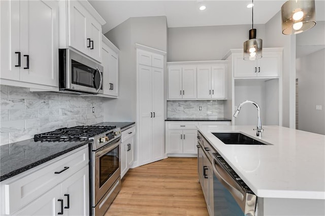 kitchen featuring stainless steel appliances, white cabinetry, a sink, and light wood-style flooring