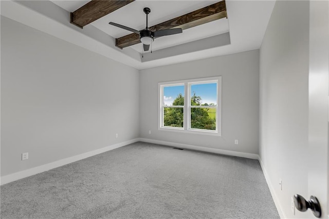 carpeted spare room with ceiling fan, visible vents, baseboards, a tray ceiling, and beamed ceiling