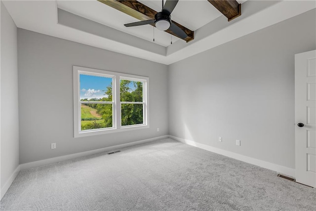 carpeted empty room with visible vents, a tray ceiling, and baseboards