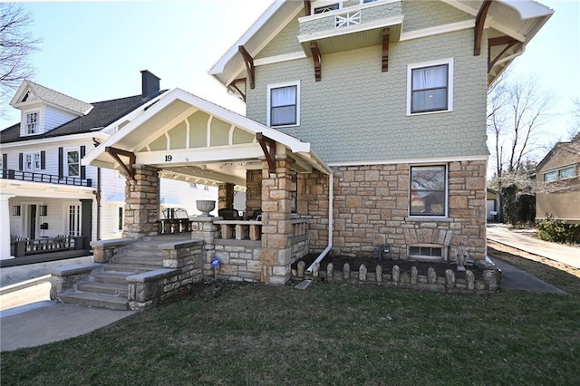 rear view of house featuring a yard and stone siding