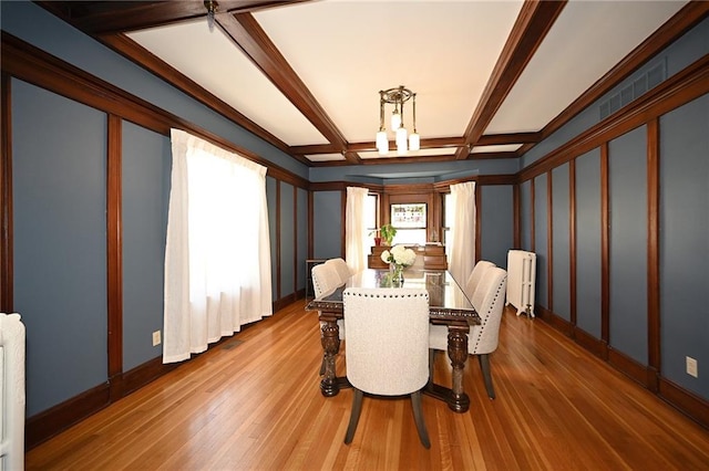 dining room featuring baseboards, radiator heating unit, beam ceiling, wood finished floors, and coffered ceiling