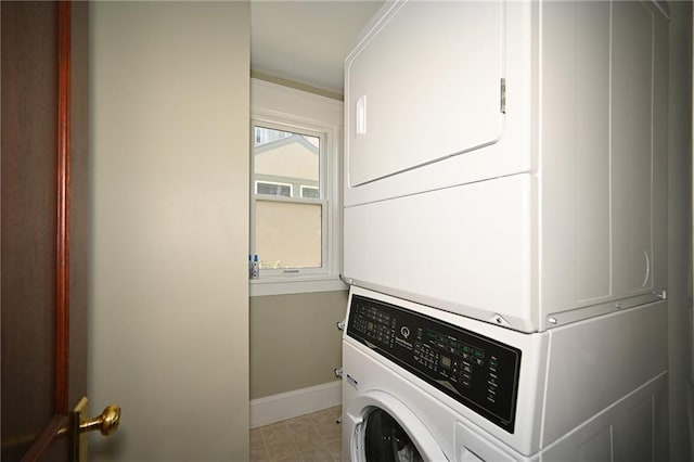 laundry room featuring baseboards, laundry area, and stacked washer / dryer