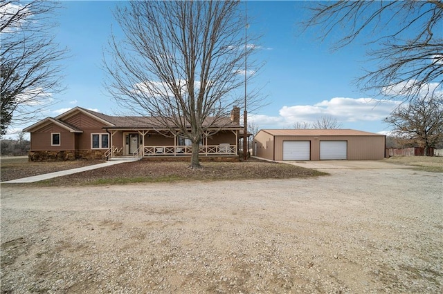 single story home with a garage, covered porch, an outdoor structure, and a chimney