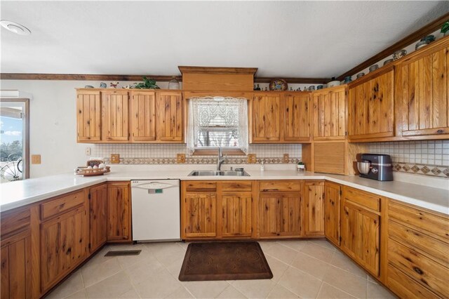 kitchen featuring tasteful backsplash, light countertops, white dishwasher, and a sink