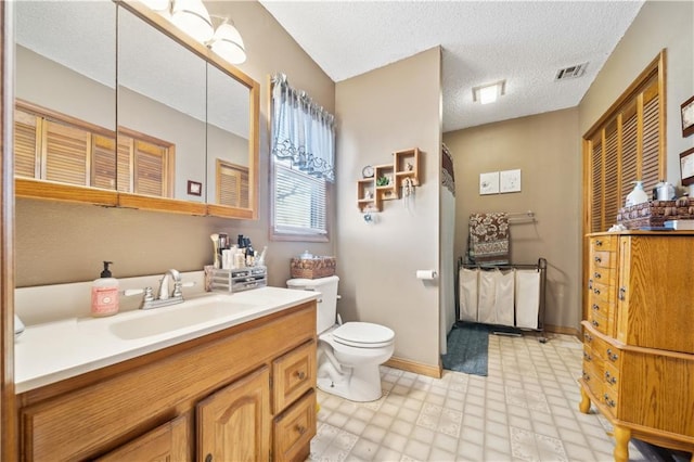 bathroom with a textured ceiling, toilet, vanity, visible vents, and tile patterned floors