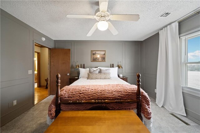 bedroom featuring a textured ceiling, carpet floors, visible vents, and a decorative wall