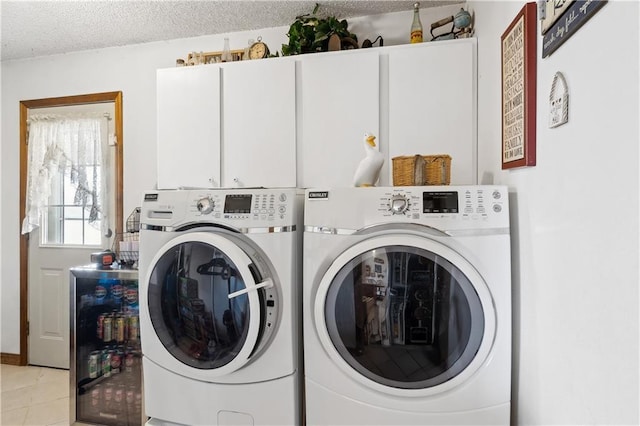 washroom featuring a textured ceiling, wine cooler, light tile patterned flooring, separate washer and dryer, and cabinet space