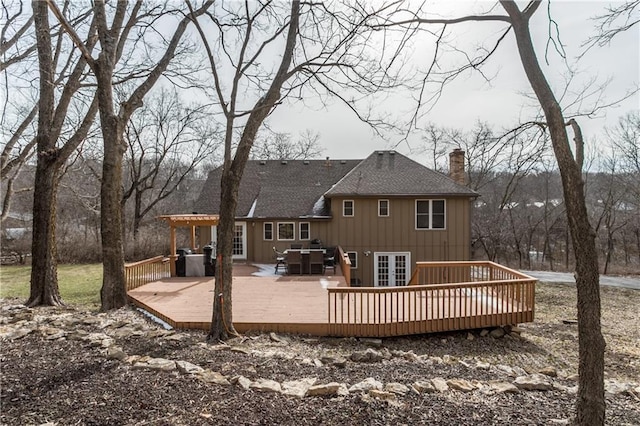 rear view of property featuring roof with shingles, a chimney, a deck, and french doors