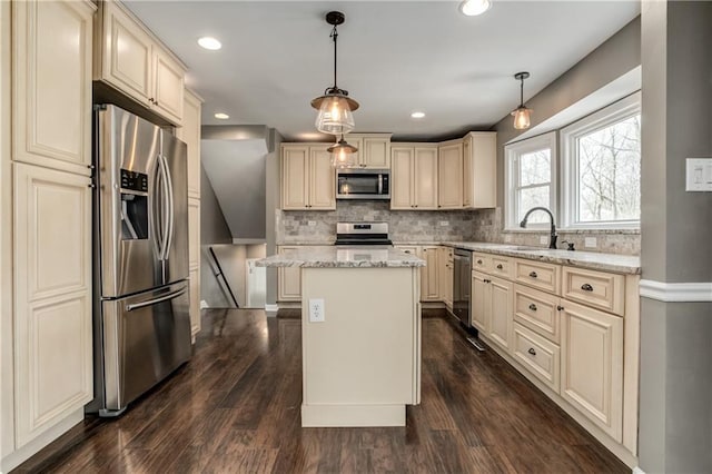 kitchen featuring backsplash, cream cabinets, stainless steel appliances, and a sink