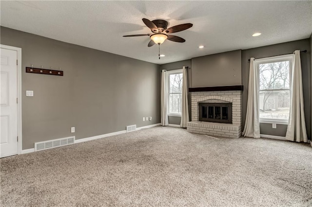 unfurnished living room with baseboards, visible vents, a fireplace, and carpet flooring