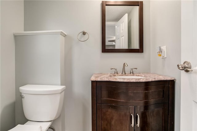 bathroom with vanity, toilet, and a textured ceiling