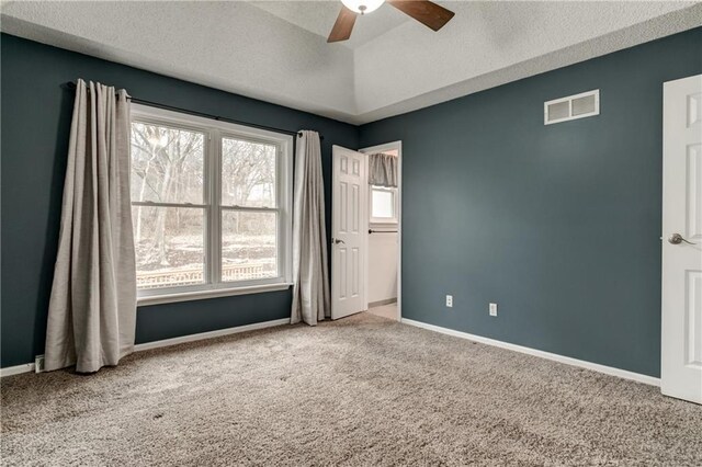 carpeted spare room featuring lofted ceiling, visible vents, a ceiling fan, a textured ceiling, and baseboards