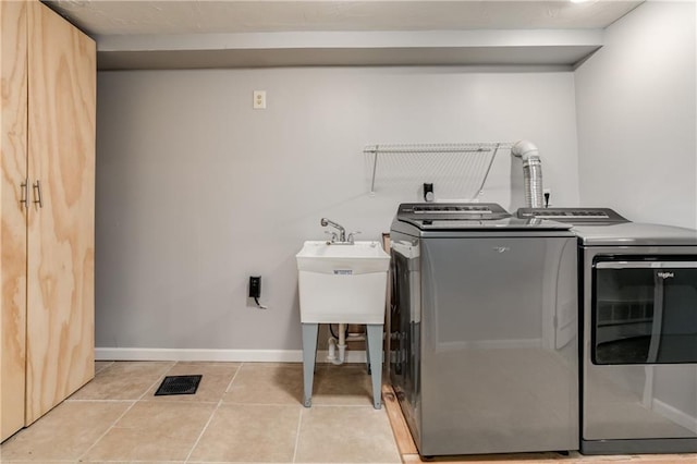 washroom with laundry area, light tile patterned floors, baseboards, visible vents, and washing machine and clothes dryer