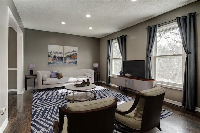 living room featuring a textured ceiling, recessed lighting, wood finished floors, and baseboards