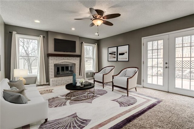 carpeted living room with baseboards, a ceiling fan, a textured ceiling, french doors, and a fireplace