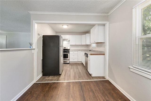 kitchen featuring a sink, ornamental molding, light wood finished floors, and stainless steel appliances