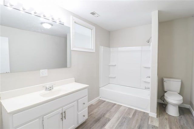 full bath featuring visible vents, toilet, wood finished floors, vanity, and shower / washtub combination