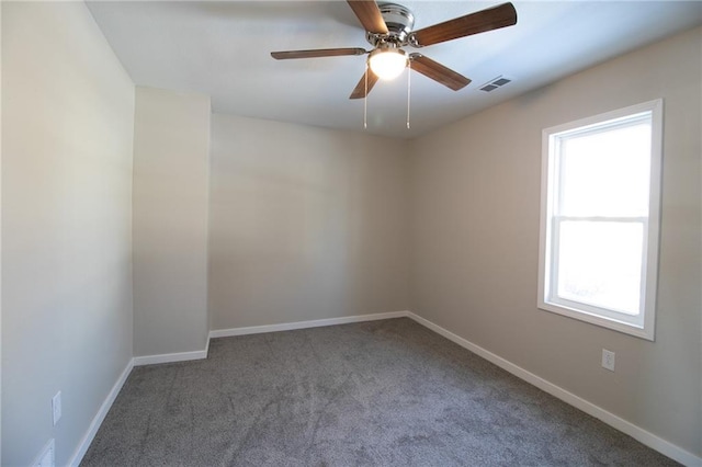 carpeted spare room with baseboards, visible vents, and a ceiling fan