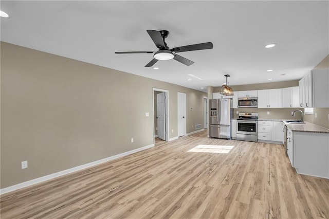 kitchen with baseboards, stainless steel appliances, light wood-style floors, white cabinetry, and a sink