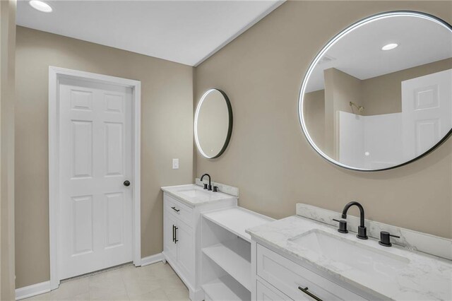 bathroom featuring baseboards, two vanities, a sink, and tile patterned floors