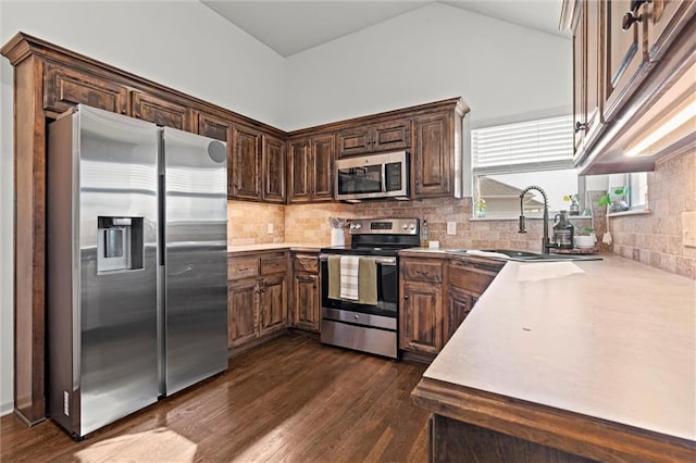 kitchen featuring a sink, tasteful backsplash, stainless steel appliances, light countertops, and dark wood-style flooring