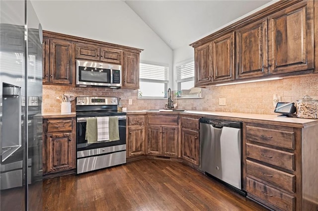 kitchen featuring backsplash, dark wood finished floors, light countertops, appliances with stainless steel finishes, and a sink