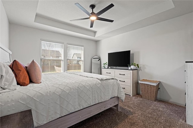 bedroom featuring a raised ceiling, light colored carpet, and ceiling fan