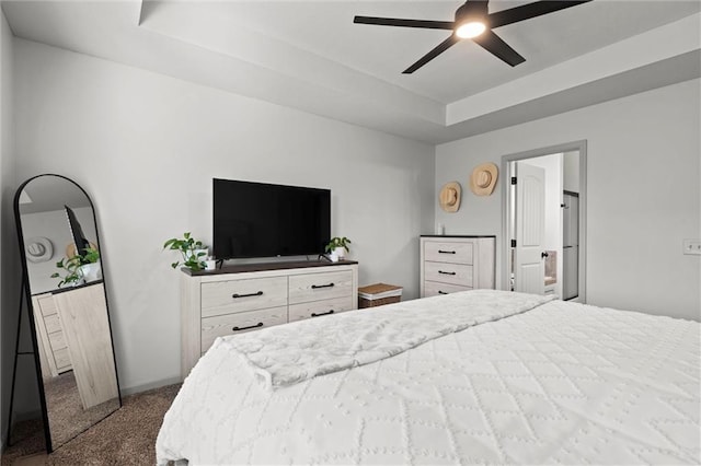 carpeted bedroom with a raised ceiling and ceiling fan