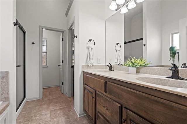 bathroom with a sink, baseboards, a shower with door, and double vanity