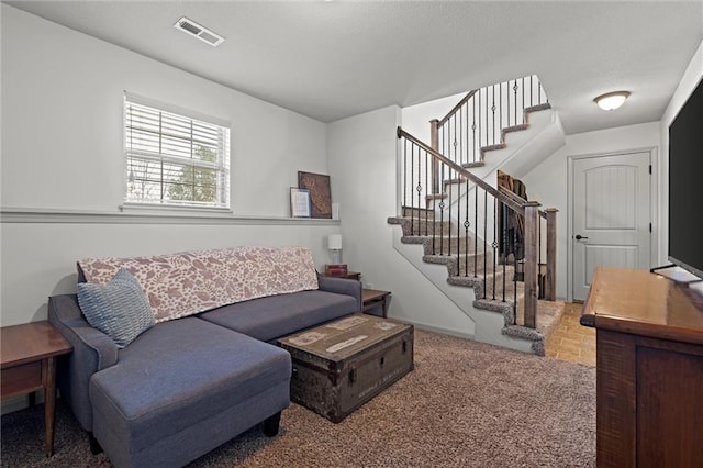 carpeted living area featuring visible vents and stairs