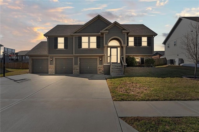 view of front of property with a front yard, fence, an attached garage, concrete driveway, and stone siding