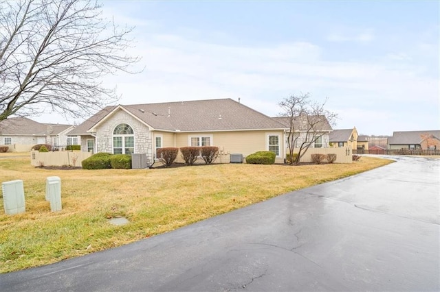 ranch-style house with fence, a front lawn, and cooling unit