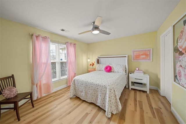 bedroom with light wood finished floors, a ceiling fan, visible vents, and baseboards