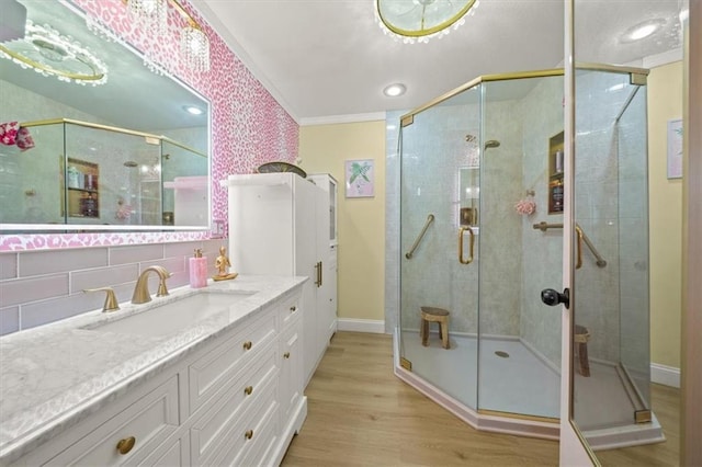 bathroom with baseboards, a shower stall, vanity, and wood finished floors