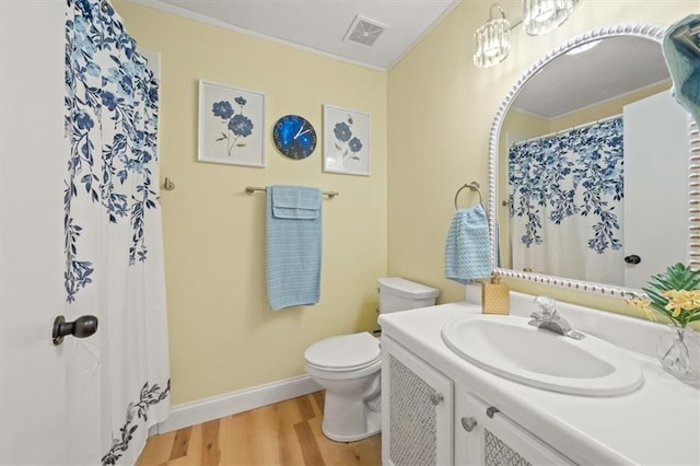 bathroom featuring toilet, wood finished floors, vanity, visible vents, and baseboards