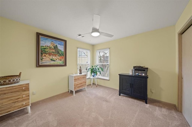 interior space featuring light colored carpet, ceiling fan, and baseboards