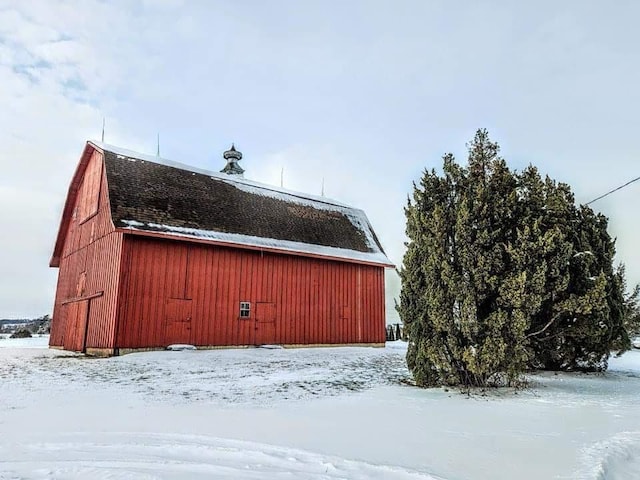 snow covered structure featuring a barn and an outdoor structure