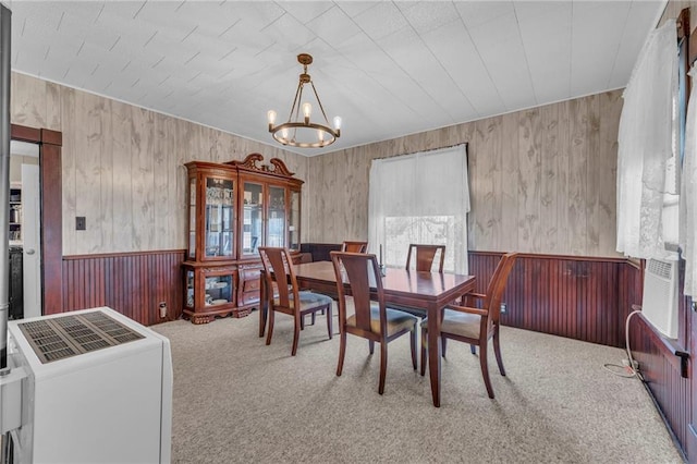 carpeted dining room with a wealth of natural light, a chandelier, and wainscoting