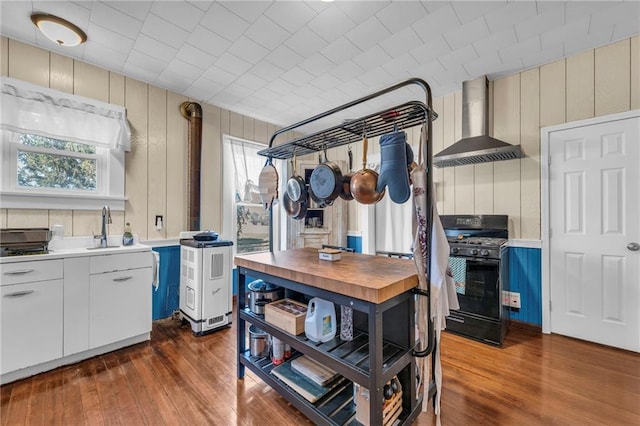 kitchen featuring black gas range, dark wood-style floors, wall chimney exhaust hood, and a sink