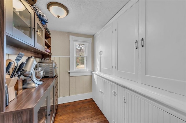 office featuring a textured ceiling, wainscoting, and dark wood-style flooring