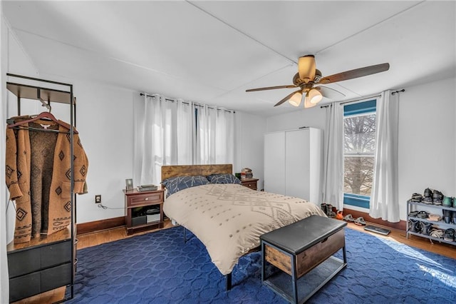 bedroom with baseboards, a ceiling fan, and dark wood-style flooring