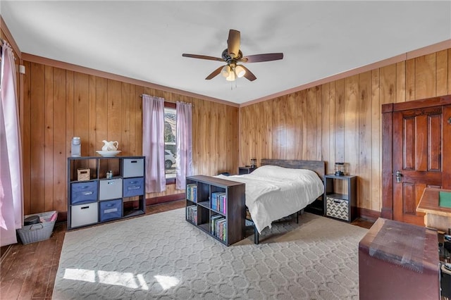 bedroom featuring wood walls, a ceiling fan, and wood finished floors