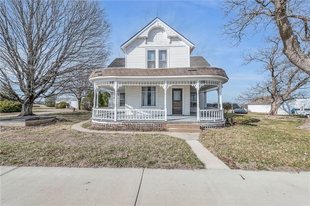 victorian home featuring a porch, a front yard, and roof with shingles