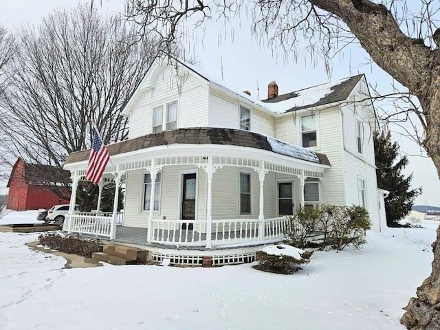 view of front facade with covered porch and a chimney