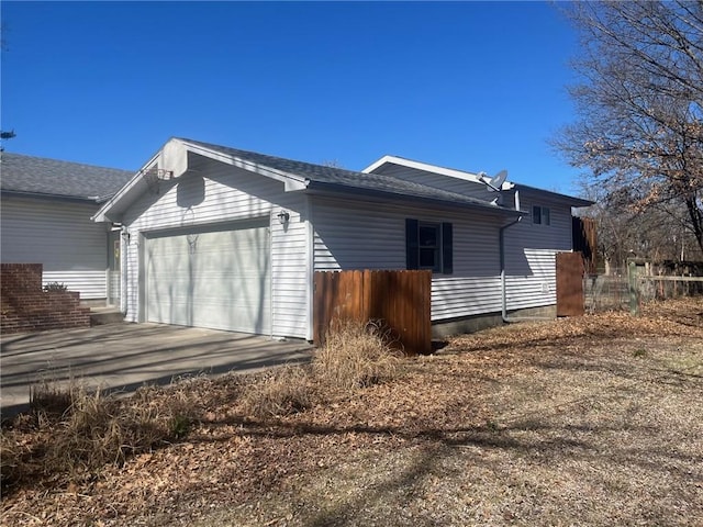 view of side of property featuring a garage, driveway, and fence